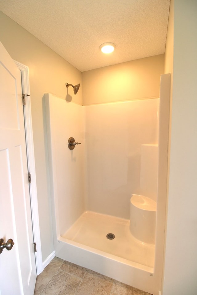 bathroom with walk in shower and a textured ceiling