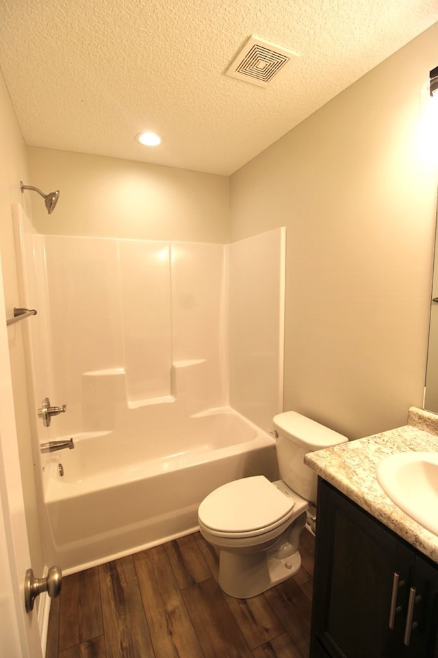 full bathroom with visible vents, toilet, a textured ceiling, vanity, and wood finished floors