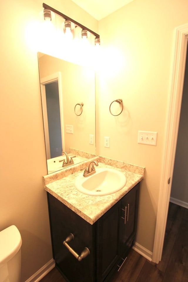 bathroom featuring vanity, baseboards, toilet, and wood finished floors