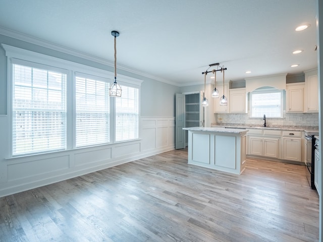 kitchen with electric range, tasteful backsplash, a kitchen island, crown molding, and light wood-style floors