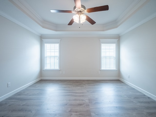 unfurnished room with plenty of natural light, a tray ceiling, and wood finished floors