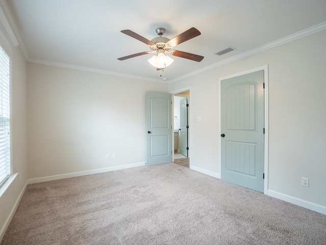 empty room with baseboards, light carpet, visible vents, and crown molding