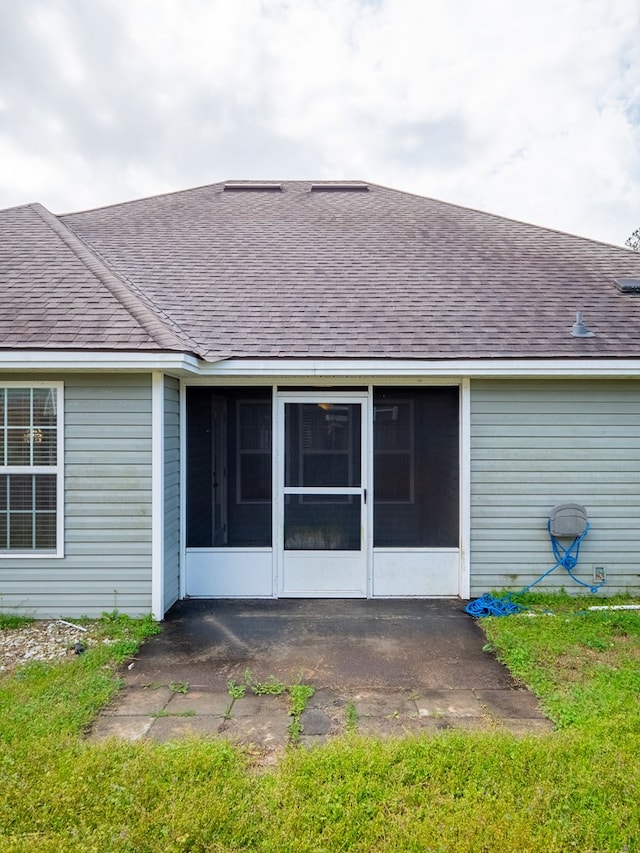 rear view of house with a shingled roof and a sunroom