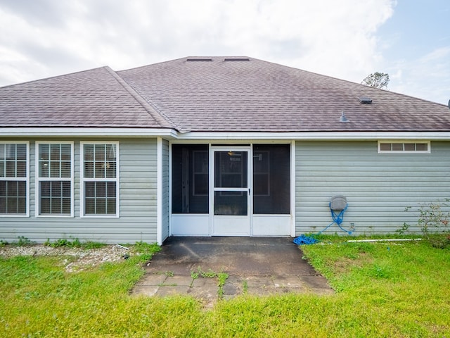 back of property with a sunroom, a shingled roof, a patio area, and a yard