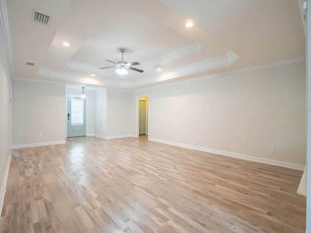 unfurnished room featuring a tray ceiling, visible vents, ceiling fan, light wood-type flooring, and baseboards