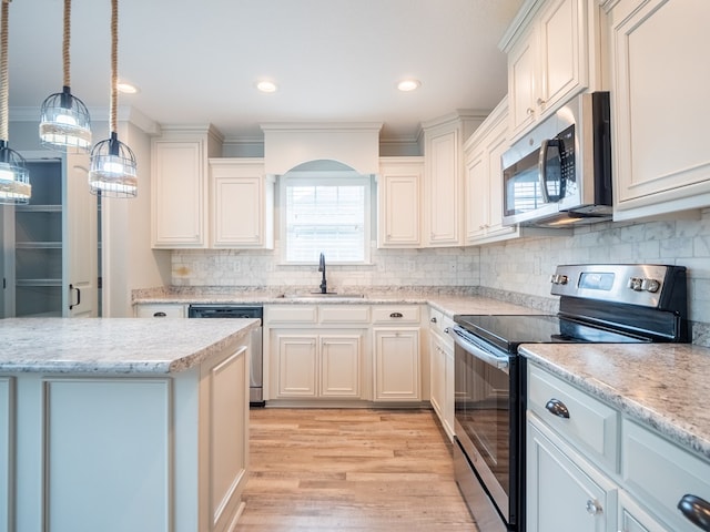 kitchen with backsplash, light wood-style flooring, appliances with stainless steel finishes, a sink, and light stone countertops