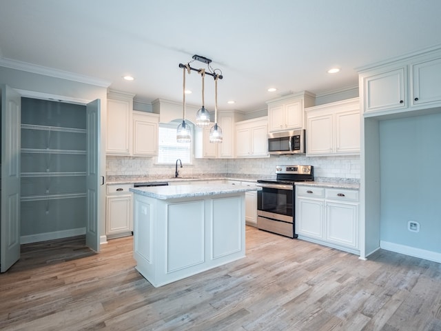 kitchen with light wood-type flooring, appliances with stainless steel finishes, decorative backsplash, and a sink