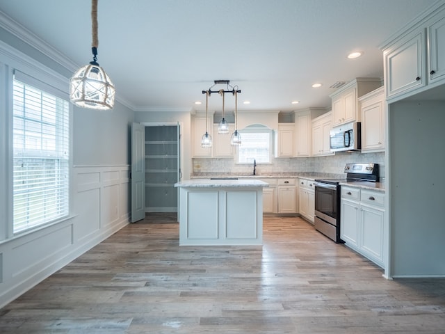 kitchen featuring stainless steel appliances, ornamental molding, backsplash, and light wood-style floors