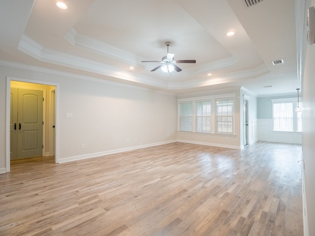 empty room featuring a ceiling fan, a tray ceiling, visible vents, and light wood finished floors