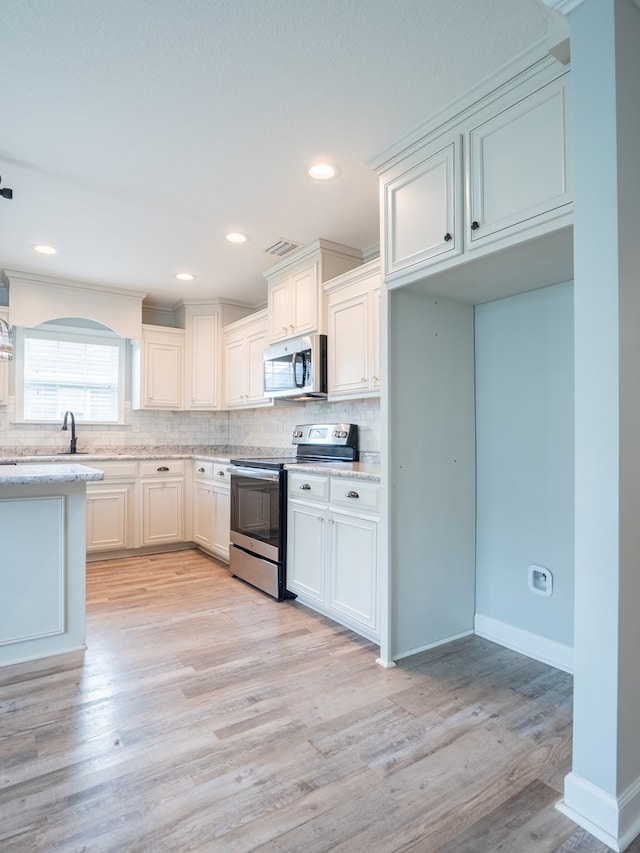 kitchen featuring light wood-type flooring, light stone countertops, tasteful backsplash, and stainless steel appliances