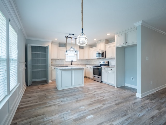 kitchen featuring stainless steel appliances, white cabinets, ornamental molding, and decorative backsplash