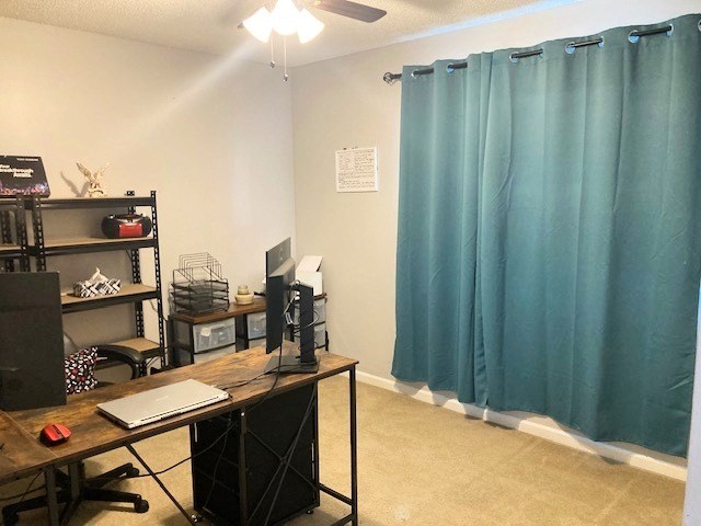 carpeted office space with baseboards and a ceiling fan