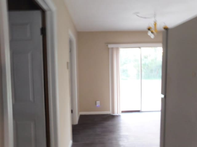 hall with baseboards, an inviting chandelier, and wood finished floors
