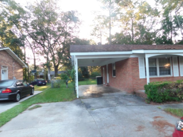 view of property exterior featuring brick siding, a carport, a yard, and concrete driveway