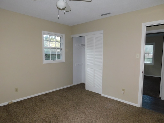 unfurnished bedroom with baseboards, a closet, dark carpet, and visible vents