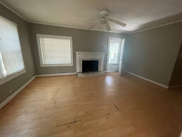 1900 N Barack Obama Blvd, Valdosta, GA 31601 - unfurnished living room featuring a ceiling fan, a tiled fireplace, ornamental molding, baseboards, and light wood-style floors