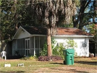 view of outdoor structure with a sunroom and a lawn