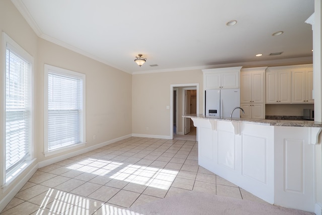 kitchen featuring light tile patterned floors, white fridge with ice dispenser, and ornamental molding