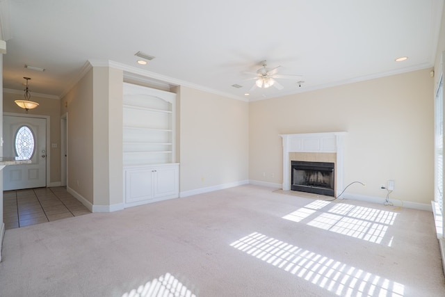 unfurnished living room featuring a tiled fireplace, ceiling fan, light colored carpet, and ornamental molding