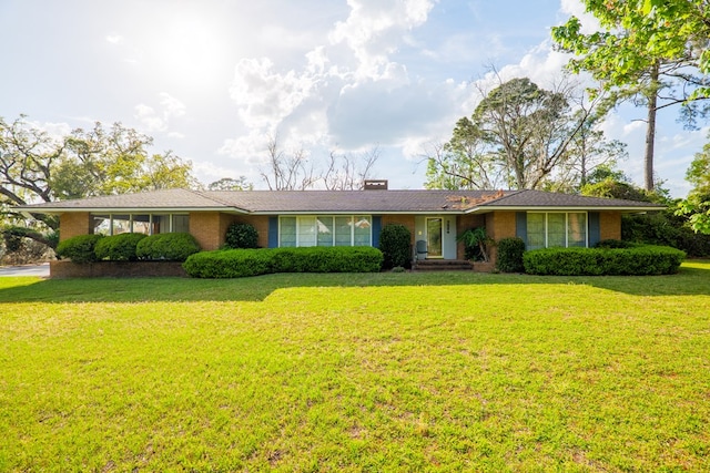 ranch-style home with brick siding, a chimney, and a front yard