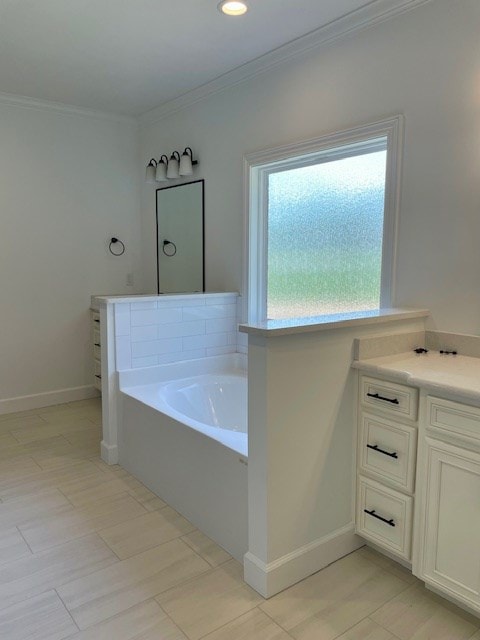 bathroom with baseboards, vanity, a bath, and crown molding