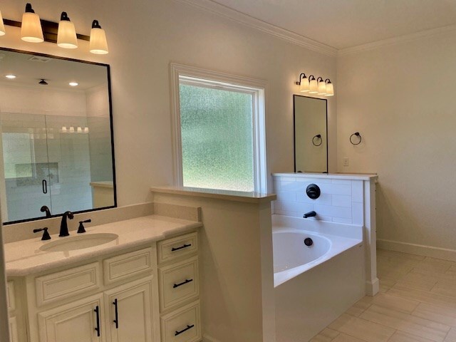 full bathroom featuring a garden tub, crown molding, a stall shower, vanity, and baseboards