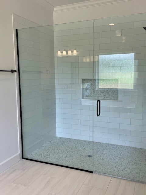 full bathroom with a stall shower, crown molding, and wood finished floors