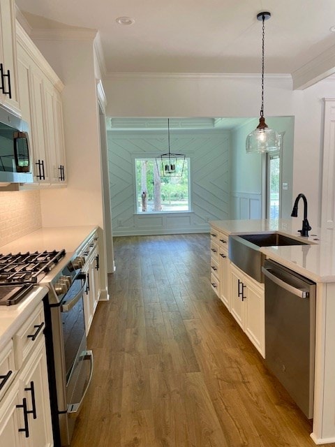 kitchen with dark wood finished floors, a sink, stainless steel appliances, crown molding, and backsplash