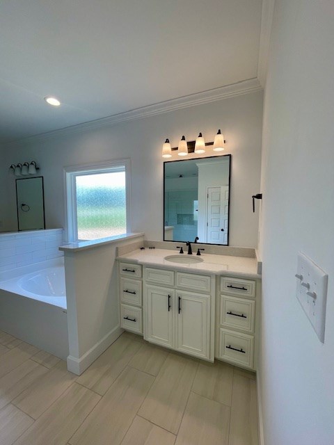 full bathroom featuring a bath, baseboards, vanity, and crown molding