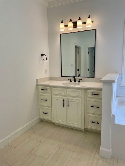 bathroom featuring baseboards, ornamental molding, and vanity