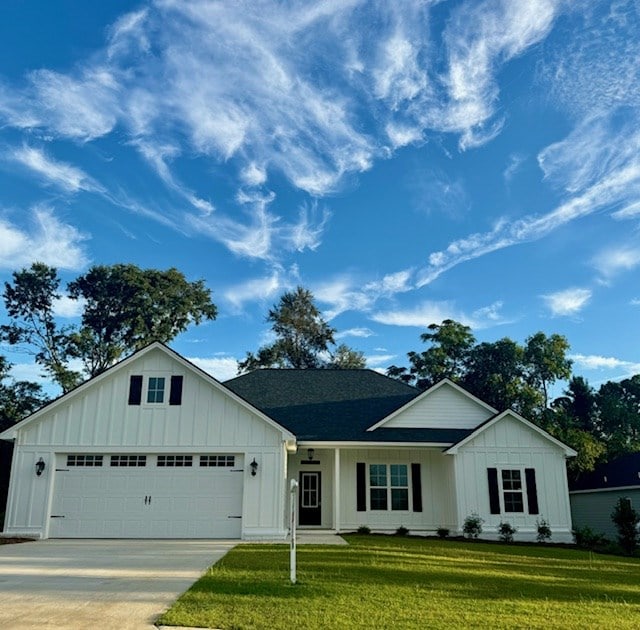 view of front of home featuring a shingled roof, an attached garage, board and batten siding, a front yard, and driveway