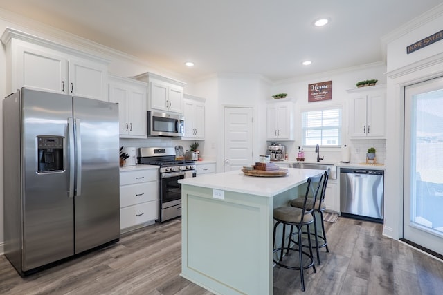kitchen featuring stainless steel appliances, light countertops, a center island, tasteful backsplash, and white cabinetry