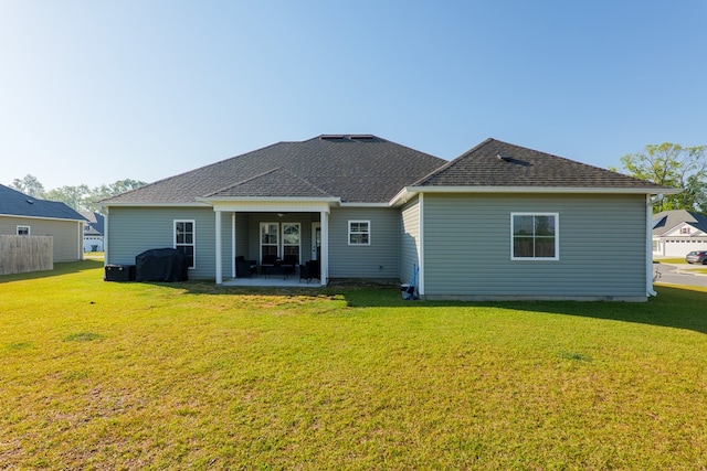 back of property featuring ceiling fan, roof with shingles, a yard, and a patio