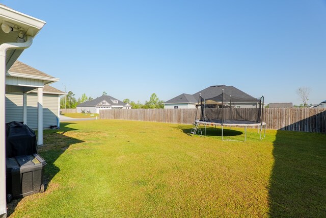 view of yard with a trampoline and a fenced backyard