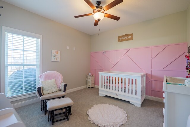 bedroom with ceiling fan, carpet, and a nursery area