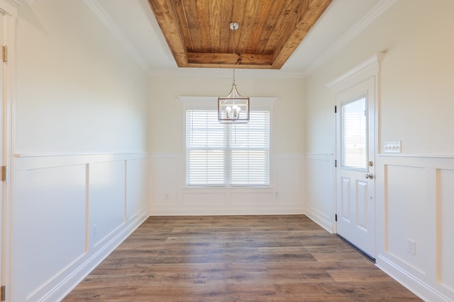 unfurnished dining area featuring dark hardwood / wood-style flooring, a raised ceiling, crown molding, and an inviting chandelier