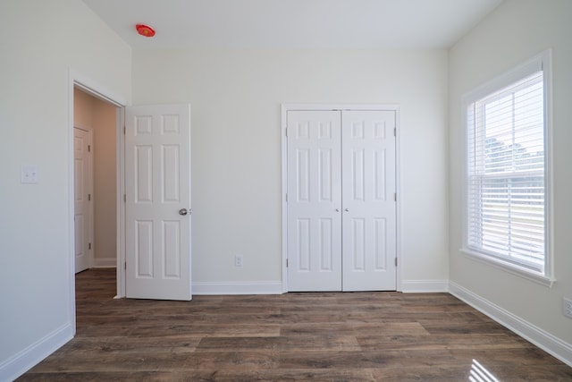 unfurnished bedroom with a closet and dark wood-type flooring