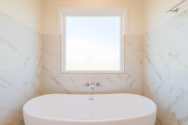 bathroom featuring tile walls and a bathing tub