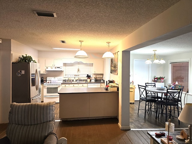 kitchen featuring pendant lighting, white appliances, white cabinetry, dark hardwood / wood-style flooring, and kitchen peninsula