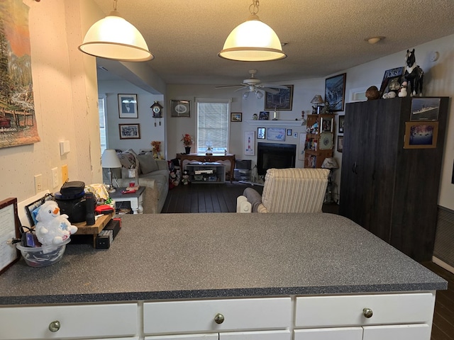 kitchen with hanging light fixtures, white cabinets, and a textured ceiling