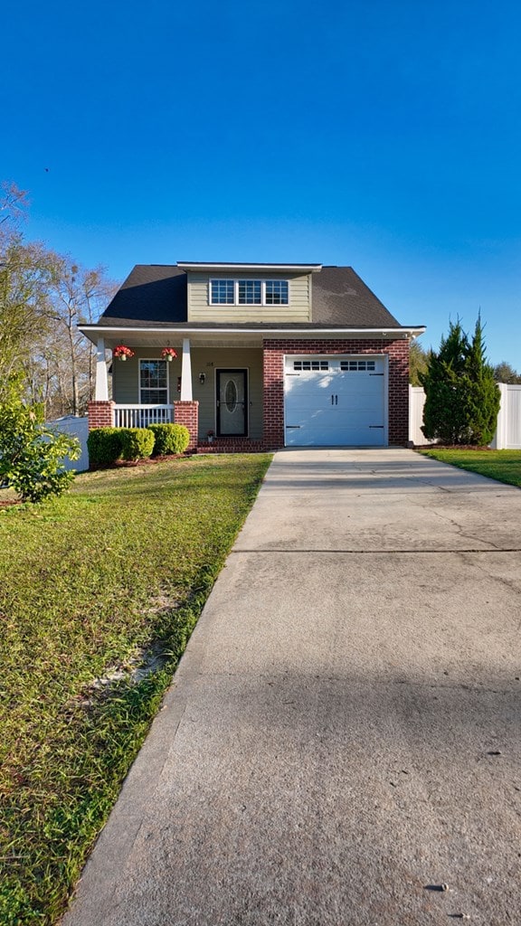 view of front of house featuring brick siding, a porch, an attached garage, and driveway