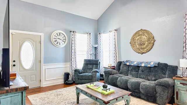 living area featuring a wainscoted wall, wood finished floors, and vaulted ceiling