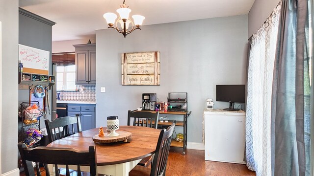 dining room with a notable chandelier, baseboards, and wood finished floors