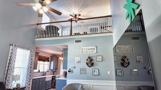 interior space with visible vents, a high ceiling, light countertops, wainscoting, and dishwasher