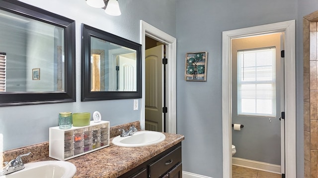 bathroom with double vanity, baseboards, tile patterned floors, and a sink