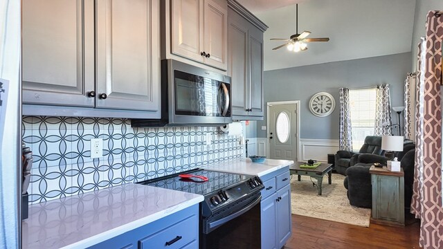 kitchen featuring stainless steel microwave, black range with electric stovetop, ceiling fan, dark wood finished floors, and wainscoting