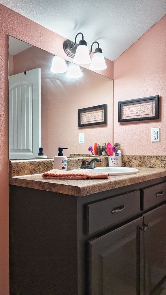 bathroom with vanity and a textured wall