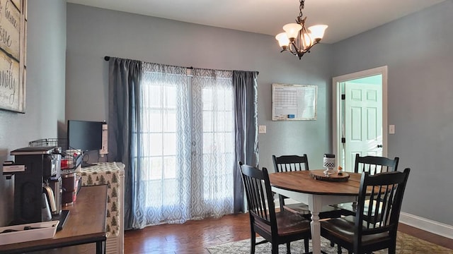 dining area featuring a chandelier, dark wood-type flooring, and baseboards