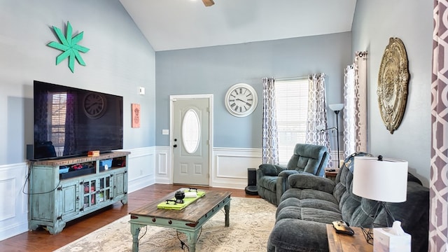 living room featuring vaulted ceiling, wood finished floors, a wainscoted wall, and ceiling fan