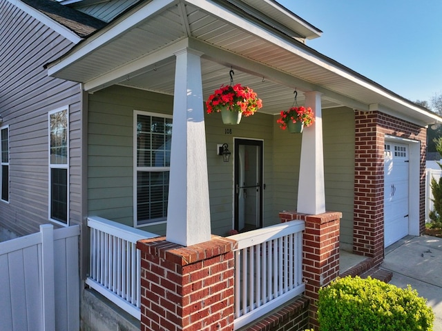 property entrance with a garage, brick siding, and a porch